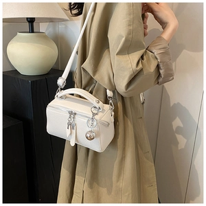 Détail du sac Boston blanc à motif litchi avec breloque boule argentée et bandoulière