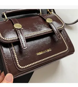 Close-up of vintage brown leather bag with gold buckle and embossed fashion lettering