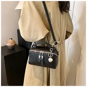 Détail du sac boston noir en cuir grainé avec finitions argentées et breloque boule
