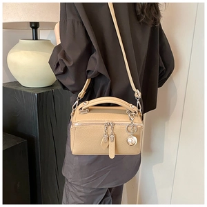 Détail du sac bandoulière en cuir grainé abricot porté par un mannequin en mode de vie