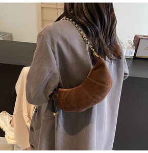 Deep coffee suede crescent bag with braided chain strap worn by a model in lifestyle setting