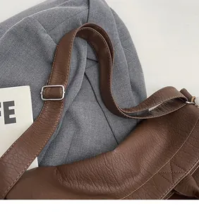 Detail of adjustable leather strap with silver buckle on brown crossbody shoulder bag