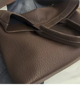 Detail of dark brown tote bag showing soft lychee texture leather and light stitching