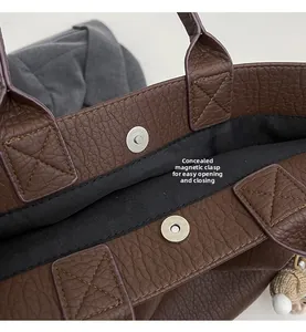 Detail of invisible magnetic closure and pebble leather texture on brown tote bag
