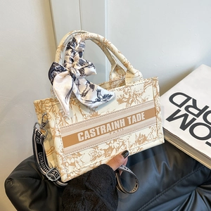 Beige canvas tote bag with retro floral print and detachable shoulder strap in a hand-held view