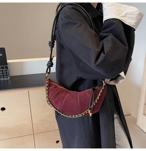 Detail of burgundy suede crescent bag with quilted pleats and knotted leather strap