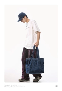 Large capacity dark blue denim tote bag with functional pockets shown on model
