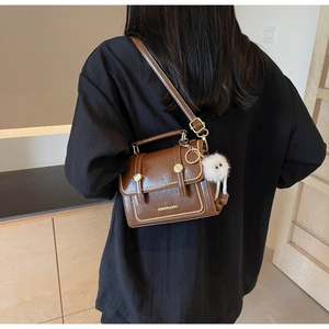 Brown vintage faux leather handbag detail with plush monster charm and metal rivets
