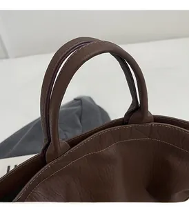 Detailed close-up of dark brown lychee texture leather handle and reinforced stitching