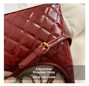 Detail of red quilted leather handbag showing adjustable strap and gold metal buckle