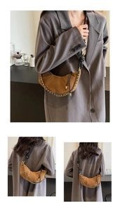 Close-up of brown suede croissant bag featuring knot leather strap and gold chain detail