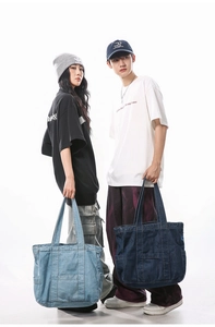 Detail view of large denim tote bags in light and dark blue with front pocket detail
