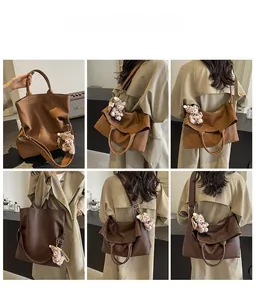Detail of a large leather tote bag featuring a cute teddy bear charm and adjustable strap