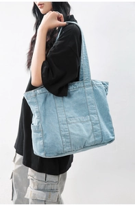 Detailed view of blue denim tote bag featuring multi-pocket design and visible stitching