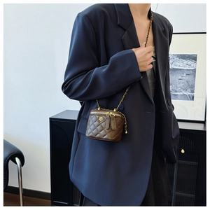 Dettaglio di una mini borsa a scatola marrone trapuntata con catena dorata su blazer blu
