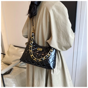 Close-up of black quilted leather shoulder bag with gold chain and turn-lock closure