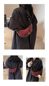 Detail view of burgundy crescent hobo bag with gold chain and black leather strap