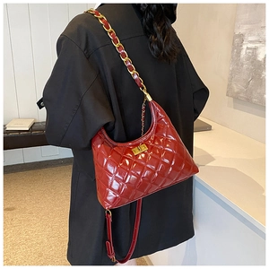 Close-up of red quilted leather shoulder bag with gold chain strap and turn-lock closure