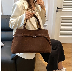 Detail of large dark brown suede tote bag with adjustable buckle strap and matte finish
