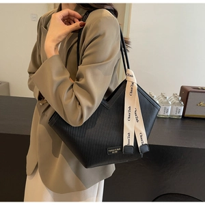 Detail of black vertical striped tote bag featuring a decorative printed ribbon and small logo