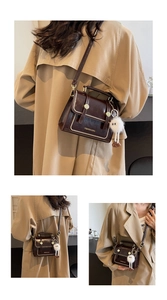Detail of vintage brown leather crossbody bag with bead edges and a plush charm