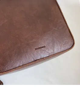 Gros plan sur la texture du sac seau en cuir marron foncé avec logo de la marque