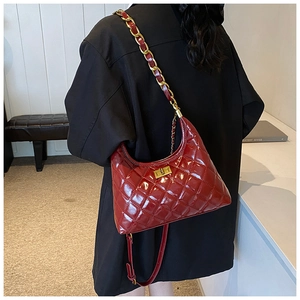 Detail of red quilted patent leather shoulder bag featuring golden twist lock and chain strap
