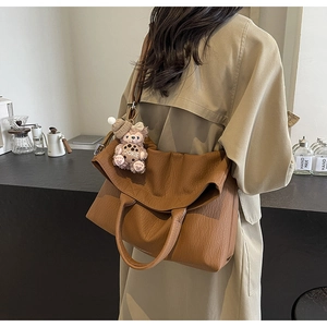 Detailed view of brown lychee grain tote bag featuring a cute bear cookie charm