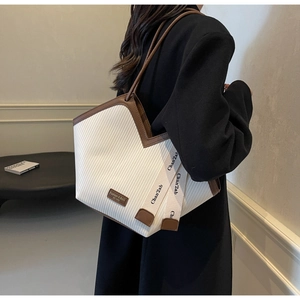 Detail of white striped tote bag with brown leather trim and V-shaped opening design