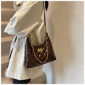 Detail of a brown quilted hobo bag with gold chain strap and turn-lock on a model