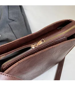 Détail de la fermeture éclair dorée et couture sur un sac seau vintage marron foncé