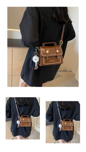 Detail of a brown vintage leather shoulder bag with beaded edges and a plush charm