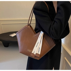 Detail of dark brown tote bag featuring unique V-cut design and vertical pleated texture