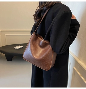 Détail du sac à bandoulière en cuir marron vintage avec fermeture éclair sur manteau
