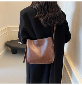 Gros plan détaillé du cuir texturé vintage marron foncé et du logo sur le sac seau