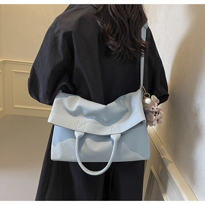 Close-up of light blue leather tote bag with lychee texture and plush animal charm