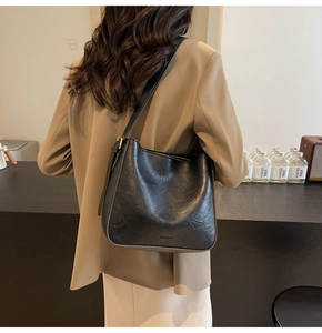 Vue latérale d'un sac seau noir en cuir grené porté avec un blazer kaki professionnel