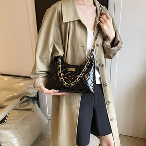 Chic black quilted hobo bag with gold chain strap and metallic lock worn with a trench coat