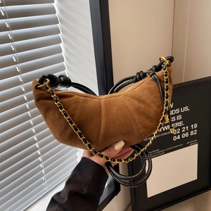 Brown frosted croissant bag with gold chain strap shown in a city life setting