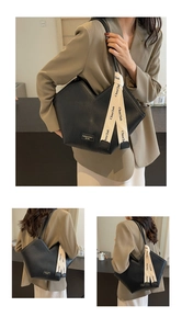 Close-up of black pleated tote bag with branded ribbon detail and textured faux leather