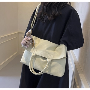 Detailed view of cream white tote bag with litchi texture and purple bear charm