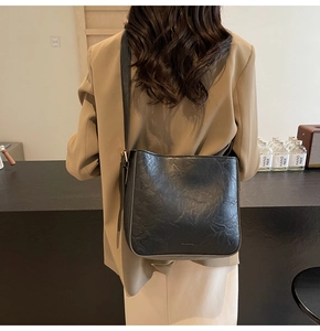 Sac seau plissé noir chic porté avec un blazer marron pour un look quotidien décontracté
