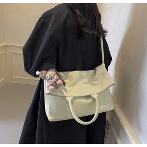 Detail of large tote bag with pleated texture and cute teddy bear charm on shoulder