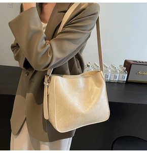 Vue détaillée d'un sac hobo crème avec bandoulière réglable sur fond sombre de studio