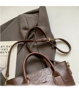 Détail de la bandoulière réglable et texture de cuir marron vintage du sac