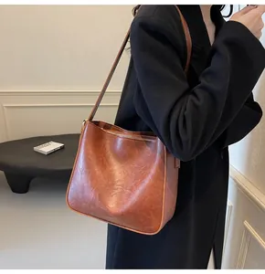 Vue latérale détaillée d'un sac seau vintage en cuir marron porté à l'épaule