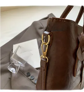 Détails de la quincaillerie dorée et du cuir marron texturé sur un sac à main de luxe