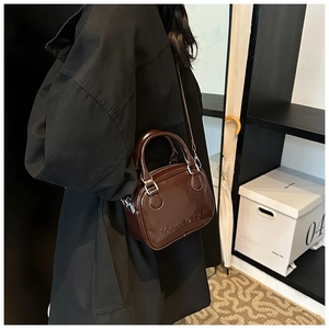 Detail of dark brown patent leather handbag with embossed Yimeiya text and metallic hardware