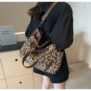 Detailed shot of large leopard print tote bag with brown leather trim on woman shoulder