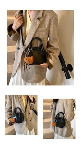 Detail of black Boston style handbag with brown plush bear charm and adjustable strap